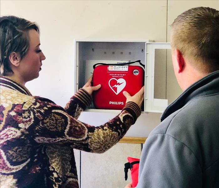 Two people holding AED.
