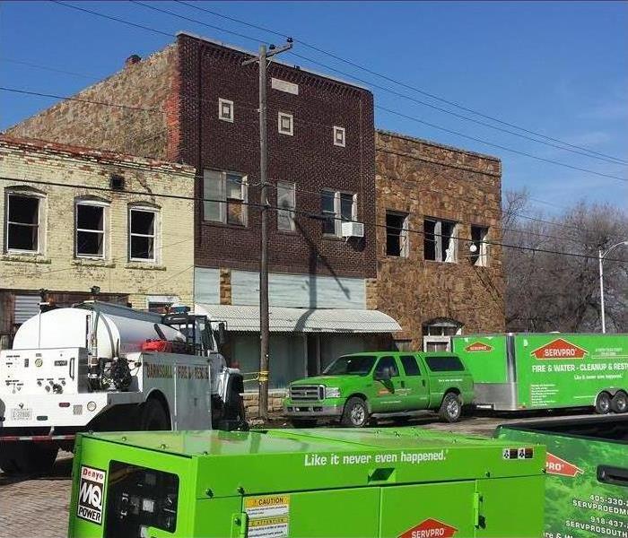 Building with smoke damage (picture taking from outside) water tank truck, green van with trailer